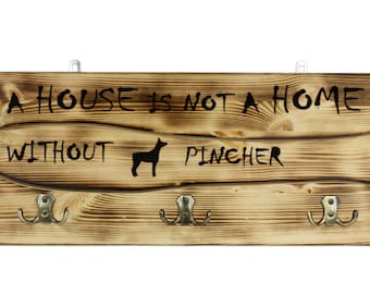 Miniature Pinscher, a wooden wall peg, hanger with the picture of a dog and the words: "A house is not a home without..."