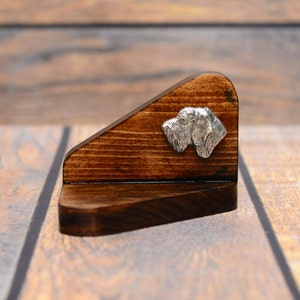 Könnte beinhalten: Ein Holzständer mit dreieckiger Form und einer dunkelbraunen Beize. Ein silberner Hundekopf aus Metall ist am Ständer befestigt.