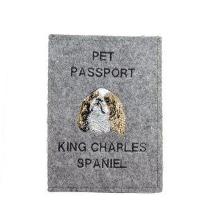 May include: Gray felt pet passport with the text "PET PASSPORT" and an embroidered image of a King Charles Spaniel with the text "KING CHARLES SPANIEL" underneath.