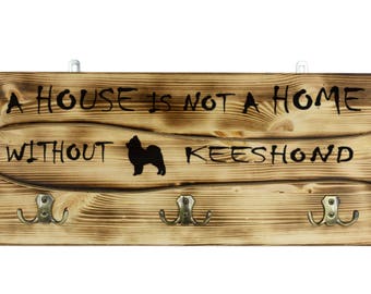 Keeshond, a wooden wall peg, hanger with the picture of a dog and the words: "A house is not a home without..."