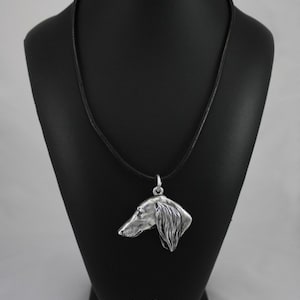 Peut inclure: Collier avec pendentif en argent représentant un profil détaillé d'un chien de race Saluki. Le collier est sur un cordon en cuir noir et présenté sur un support noir avec le texte "Art-Dog".