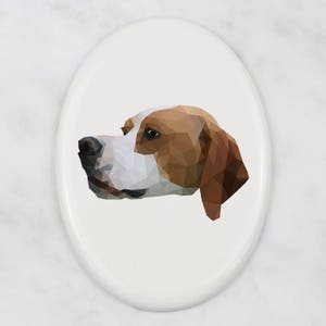 Può includere: Ornamento ovale in ceramica con un'illustrazione geometrica della testa di un cane di profilo. Il pelo del cane è raffigurato in tonalità di marrone, bianco e nero, su sfondo bianco. L'ornamento ha una finitura lucida.