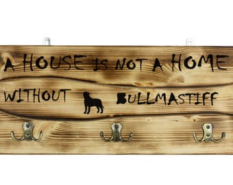 Bullmastiff, a wooden wall peg, hanger with the picture of a dog and the words: "A house is not a home without..."