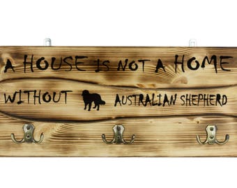 Australian Shepherd, a wooden wall peg, hanger with the picture of a dog and the words: "A house is not a home without..."