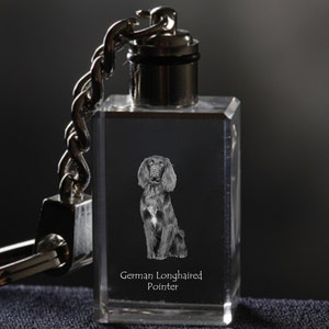 Op de afbeelding: Een heldere, rechthoekige kristallen sleutelhanger met een zilveren ketting en sluiting. De sleutelhanger heeft een grijswaardenafbeelding van een Duitse Langhaar hond en de tekst "German Longhaired Pointer". De hond zit rechtop.