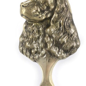 May include: A gold-colored metal sculpture of a Cocker Spaniel dog's head. The sculpture is 6.3 inches tall and 3.5 inches wide and weighs 1.51 pounds.