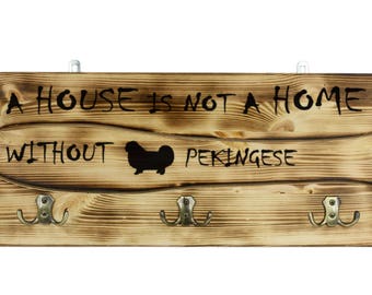 Pekingese, a wooden wall peg, hanger with the picture of a dog and the words: "A house is not a home without..."