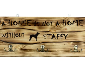 Staffordshire Bull Terrier, a wooden wall peg, hanger with the picture of a dog and the words: "A house is not a home without..."