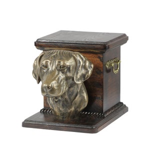 May include: A wooden pet urn with a bronze Labrador Retriever head sculpture on the front. The urn has a dark wood finish and a brass handle.