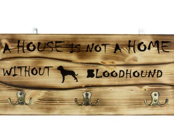 Bloodhound, a wooden wall peg, hanger with the picture of a dog and the words: "A house is not a home without..."