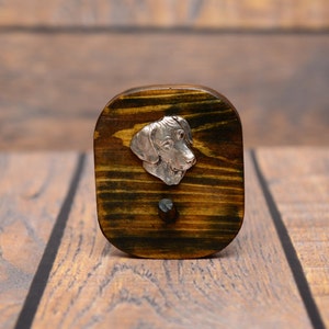 May include: A wooden plaque with a silver dog head sculpture attached. The plaque is stained a dark brown color and has a wood grain pattern.