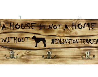 Bedlington Terrier, a wooden wall peg, hanger with the picture of a dog and the words: "A house is not a home without..."