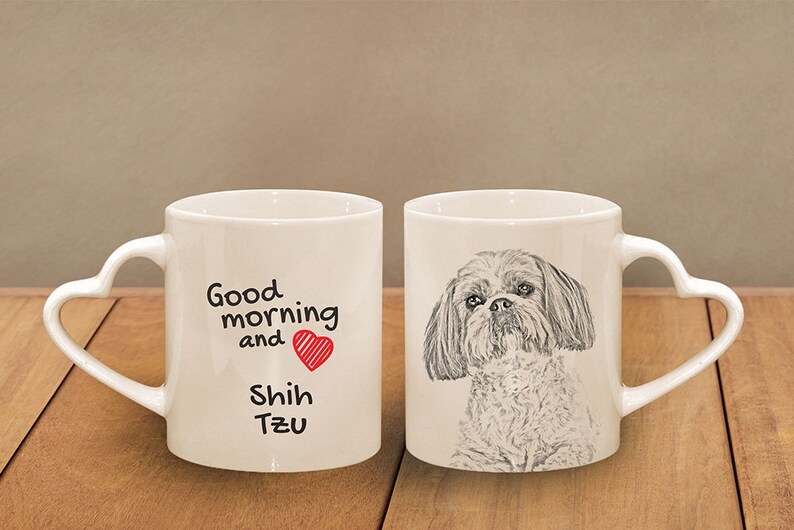 Puede incluir: Dos tazas de cer&aacute;mica blanca con asas en forma de coraz&oacute;n. Una taza presenta una ilustraci&oacute;n en blanco y negro de un perro Shih Tzu. La otra taza tiene el texto "Good morning and Shih Tzu" con un coraz&oacute;n rojo.