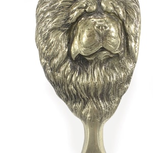 May include: A gold-colored metal sculpture of a Chow Chow dog's head. The sculpture is 6.3 inches tall and 3.1 inches wide and weighs 1.22 pounds.