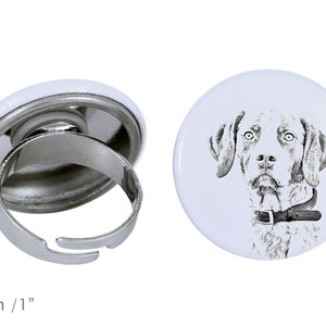 Könnte beinhalten: Ein verstellbarer Silberring mit einem weißen Knopf, der eine Schwarzweißillustration eines Hundekopfes zeigt. Der Knopf hat einen Durchmesser von 2,5 cm.