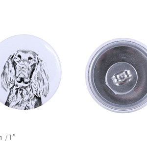 Könnte beinhalten: Ein weißer Knopf mit silberner Rückseite, der eine Schwarzweißillustration eines Springer Spaniel-Hunde头的 zeigt. Der Knopf hat einen Durchmesser von 2,5 cm.