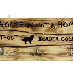 Border Collie, Kleiderbügel aus Holz an der Wand mit dem Bild eines Hundes und mit einem Motto:&quot;A house is not a home without...&quot;