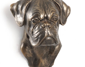 May include: Bronze sculpture of a boxer dog head, with a realistic and detailed design. The sculpture is mounted on a wall and has a distressed finish.