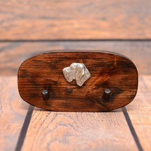 Op de afbeelding: Een houten sleutelhanger met twee haken en een metalen hondenkopontwerp. De sleutelhanger is donkerbruin en heeft een natuurlijke houtnerf.