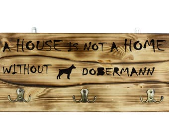 Dobermann, a wooden wall peg, hanger with the picture of a dog and the words: "A house is not a home without..."