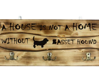 Basset Hound, a wooden wall peg, hanger with the picture of a dog and the words: "A house is not a home without..."