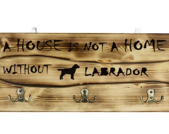 Labrador Retriever, a wooden wall peg, hanger with the picture of a dog and the words: "A house is not a home without..."