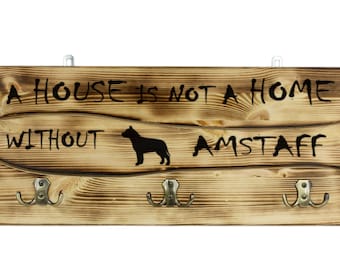 American Staffordshire Terrier, a wooden wall peg, hanger with the picture of a dog and the words: "A house is not a home without..."