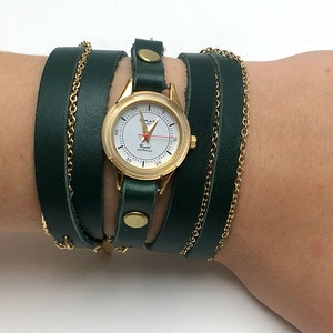 May include: A green leather wrap watch with a gold face and gold chain accents. The watch face has a white background with black numbers and a red second hand.