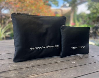 Puede incluir: Dos bolsas de cuero negro con cremalleras plateadas y texto hebreo blanco. La bolsa más grande tiene el texto "Shema Yisrael H' Elokeinu H' Echad". La bolsa más pequeña tiene el texto "Yevarechecha H' Veyishmerecha".