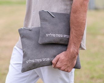 Puede incluir: Dos estuches de cuero gris con texto hebreo blanco que dice "ברוכים הבאים  סולידן"  que se traduce como "Bienvenido Solidan".