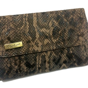 Pode incluir: Uma carteira de mão marrom de pele de cobra com um logotipo de metal dourado que diz "Sigal Levi"