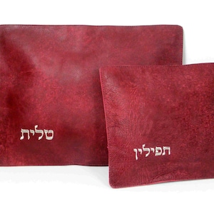 May include: Two burgundy leather prayer shawls with Hebrew embroidery. The larger shawl has the word "S'khila" embroidered on it, and the smaller shawl has the word "Habdala" embroidered on it.