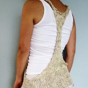 May include: A white tank top with a beige crocheted vest. The vest is open at the back and has a unique design.