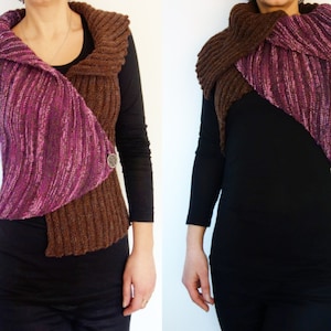 Può includere: Un gilet di maglia marrone e viola con collo a scialle e chiusura a bottone. Il gilet è indossato sopra una camicia nera a maniche lunghe.