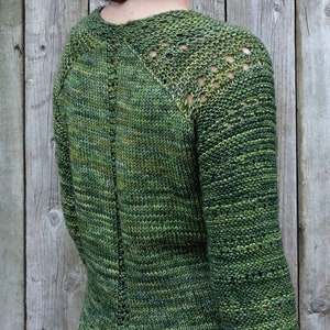 May include: A green knitted sweater with a lace pattern on the sleeves and a split hem.