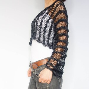 May include: Black crochet top with long sleeves and a striped pattern. The top is cropped and has a loose fit.
