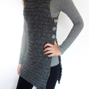 May include: A gray crochet vest with a long, asymmetrical hemline and button closures on the side.