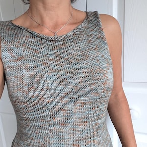 May include: A sleeveless knit top in a speckled pattern of gray, blue, and rust-colored threads. The top has a scoop neckline and a fitted silhouette. The fabric appears to be a soft, textured knit, suitable for warm weather.