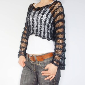 May include: A black and white striped crochet top with long sleeves. The top is cropped and has a loose fit.