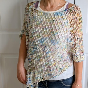 Puede incluir: Un top de crochet blanco con un patrón de hilo multicolor. El top tiene un ajuste holgado y un dobladillo ligeramente asimétrico.