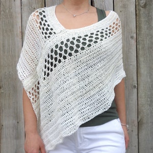 Peut inclure: Un poncho en crochet blanc avec un motif ajouré délicat. Le poncho a un col large et fluide et des manches courtes.