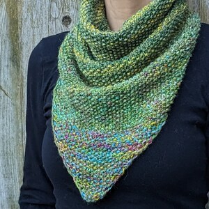 May include: A green, yellow, and blue triangular scarf with a textured knit pattern.