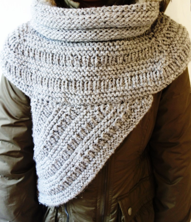 Puede incluir: Una bufanda de cuello de tortuga de punto gris con forma triangular. La bufanda est&aacute; hecha de un hilo suave y texturizado, perfecta para mantenerse caliente en invierno.