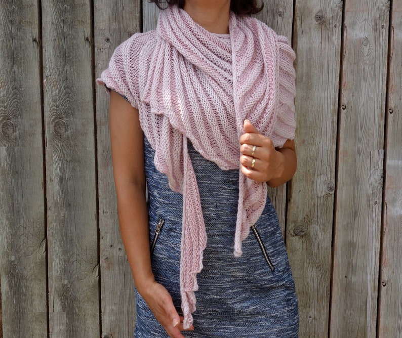 May include: A pink knitted shawl with a lacy texture, draped over a person's shoulders.