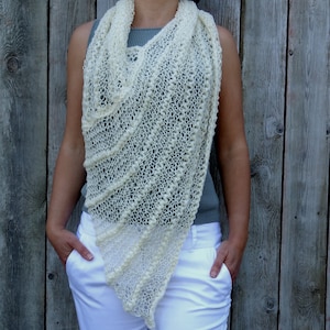 May include: A white crocheted shawl with a delicate openwork pattern. The shawl is draped around a person's shoulders and neck.