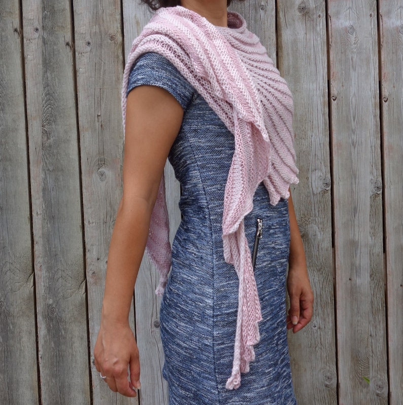 May include: A pink and white striped knitted shawl with a fringed edge. The shawl is draped over a person's shoulders and is worn with a blue and grey dress.
