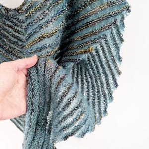 Może przedstawiać: Szal z dzianiny w niebiesko-zielone pasy z fakturowanym wzorem. Szal wykonany jest z miękkiej, lekkiej przędzy.