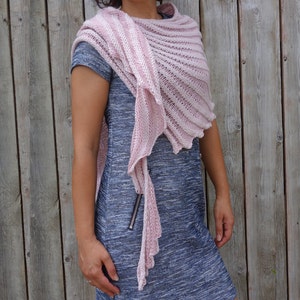 May include: A pink and white striped knitted shawl with a fringed edge. The shawl is draped over a person's shoulders and is worn with a blue dress.