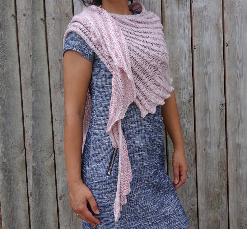 May include: A pink and white striped knitted shawl with a fringed edge. The shawl is draped over a person's shoulders and is worn with a blue dress.