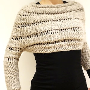 May include: A beige knitted cropped sweater with a loose fit and long sleeves. The sweater has a delicate openwork pattern.